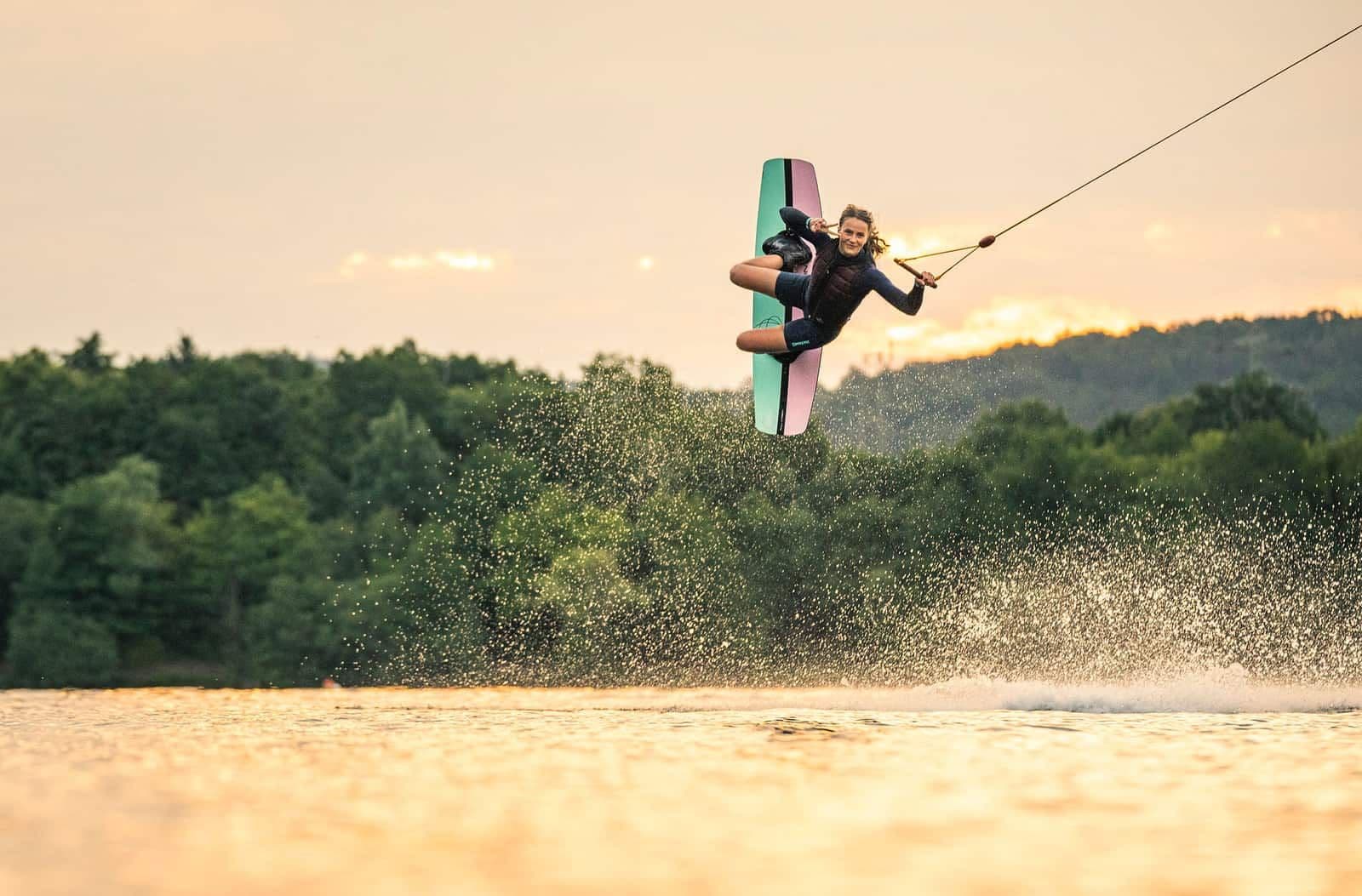 Wakeboarderin im Sprung über dem Alfsee im Abendlicht